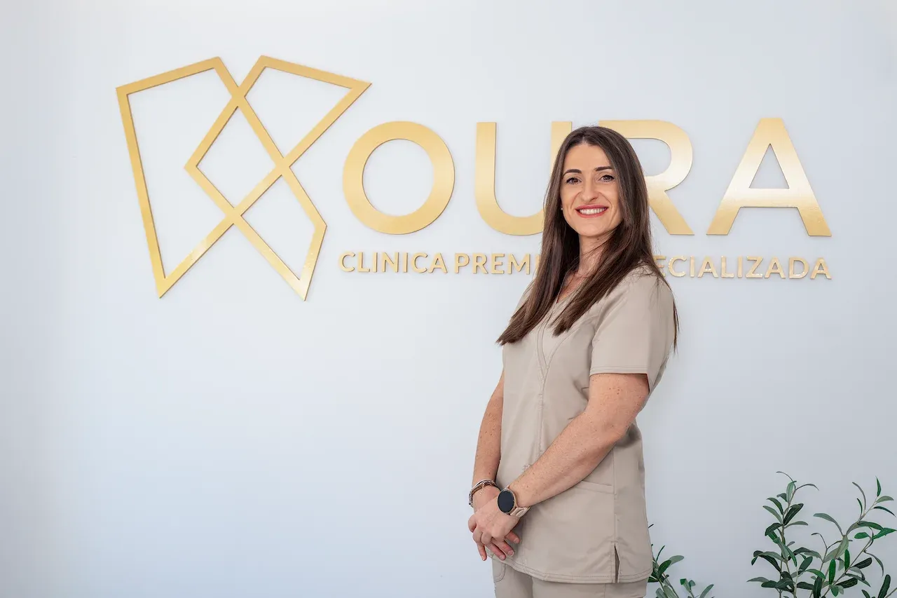 Ángela, profesional de Koura Dental Plus, posando junto al logotipo de la clínica en Madrid.